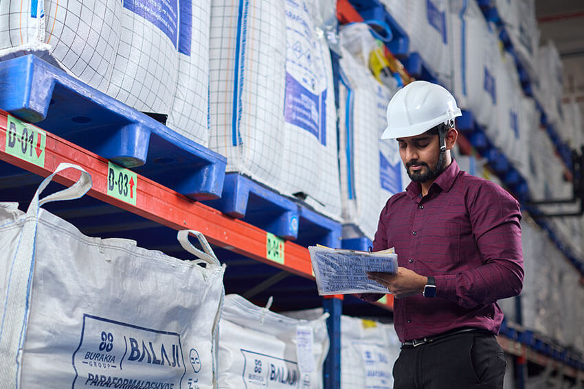 Employee taking notes at warehouse around the white bags