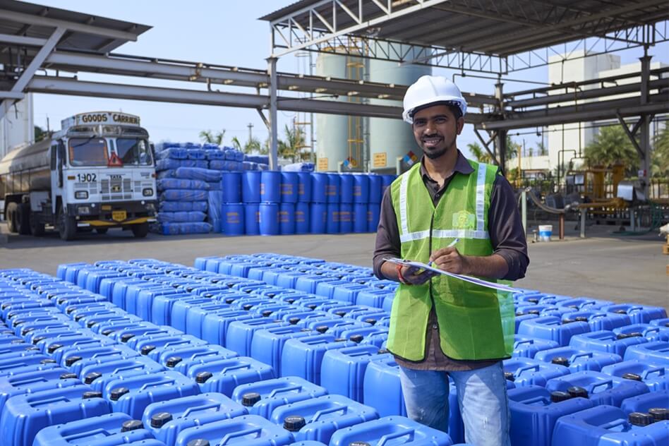 Worker with a note in hand around the blue containers of formaldehyde at Balaji Formalin