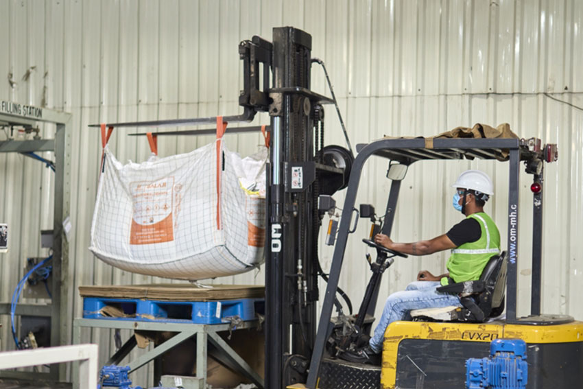 Worker lifting Urea formaldehyde bag with fork lifter truck