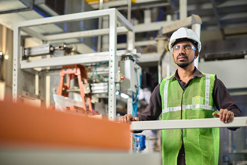 A worker standing in Formaldehyde manufacturing factory with green jacket and glasses